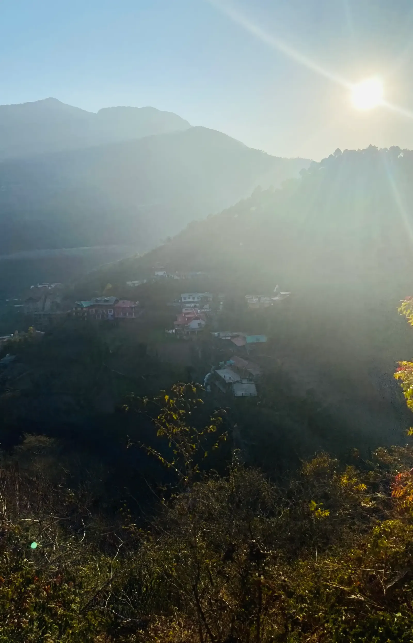 Sun shining over a hazy valley with a hillside village