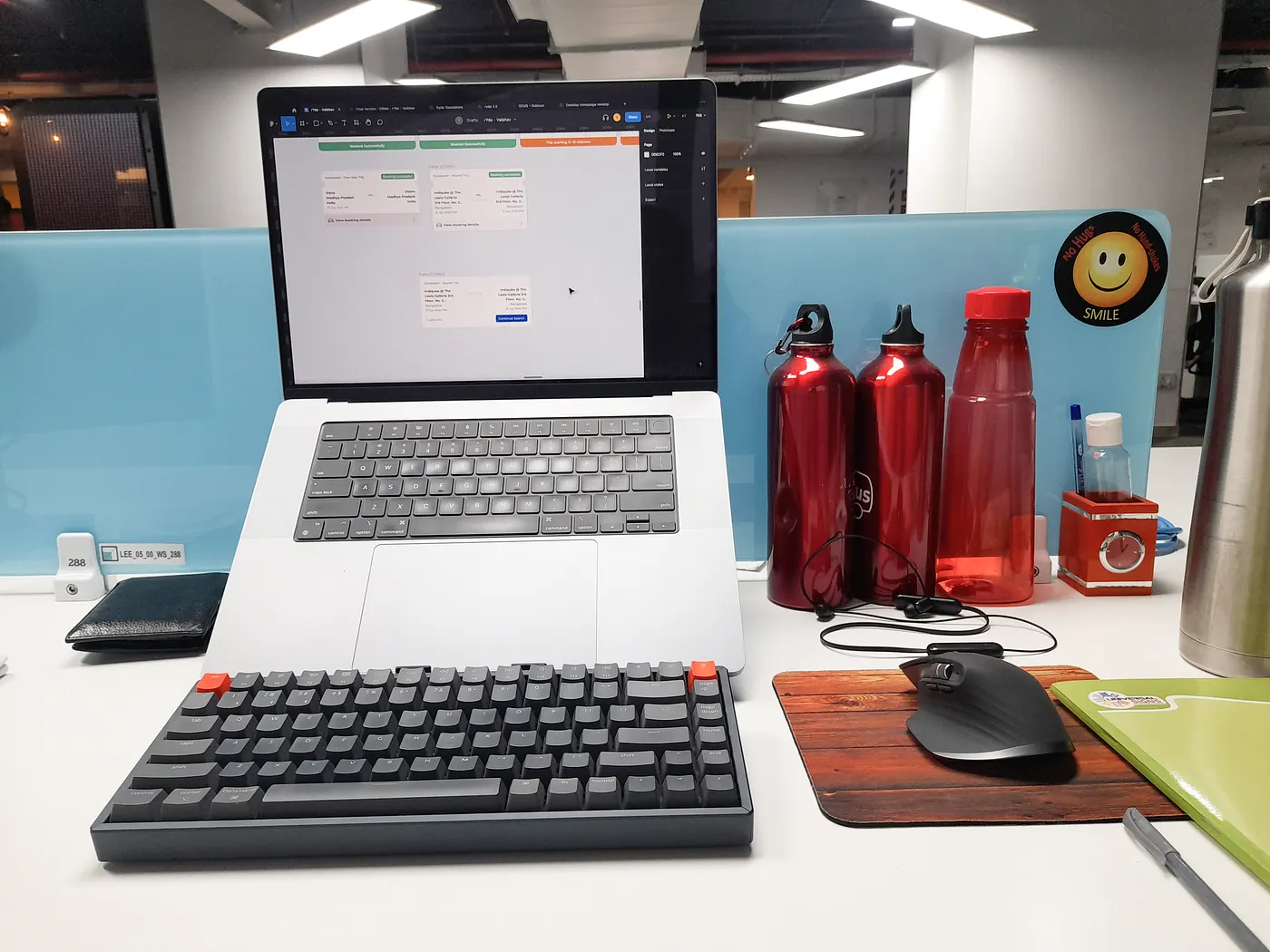 Desk setup at the redBus office with a MacBook, keyboard and redBus water bottles
